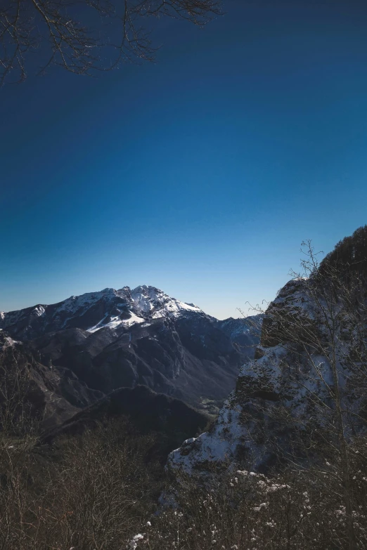 a man riding skis down a snow covered slope, a picture, unsplash contest winner, les nabis, distant mountain range, standing on a cliffside, larapi, clear blue sky