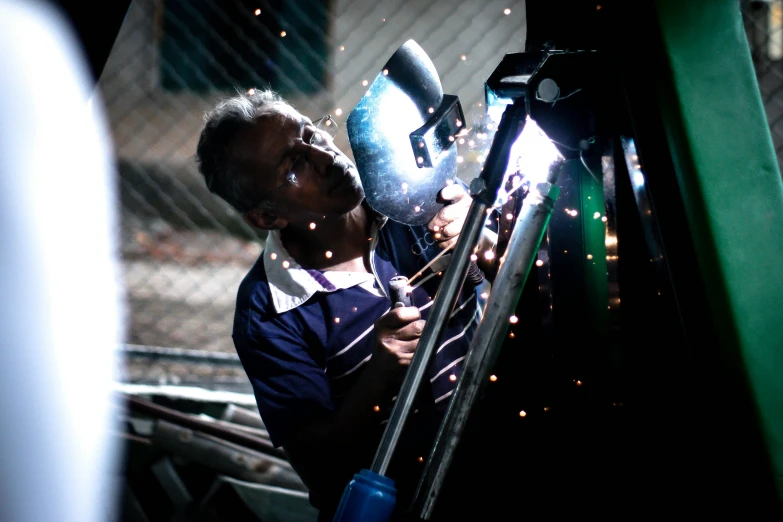 a welder is working on a piece of metal, a portrait, by Alejandro Obregón, pexels contest winner, avatar image, night time scene, with mechanical arms that fix it, sri lanka