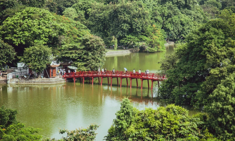 a bridge over a body of water surrounded by trees, inspired by Torii Kiyomasu, são paulo, mirror lake, vibrant red and green colours, bao pnan