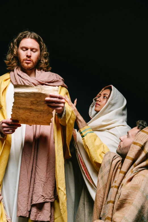 a group of people standing around a man reading a book, by Jason Felix, dressed like jesus christ, golden robes, ( ( theatrical ) ), pastoral
