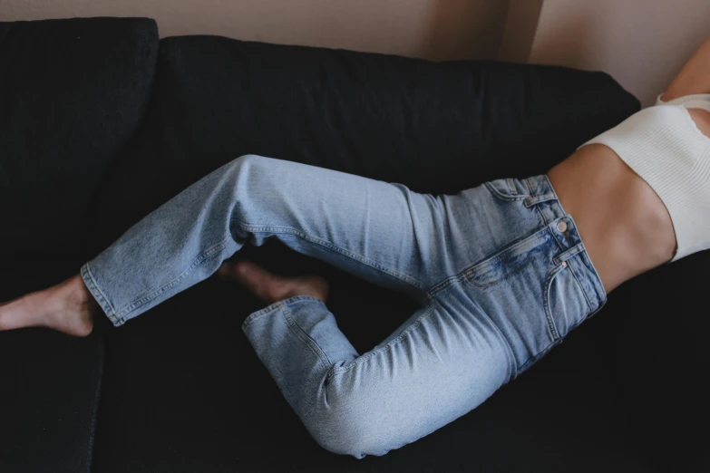 a woman laying on top of a black couch, inspired by Elsa Bleda, trending on pexels, happening, jeans pants, on a table, bella poarch, sydney hanson