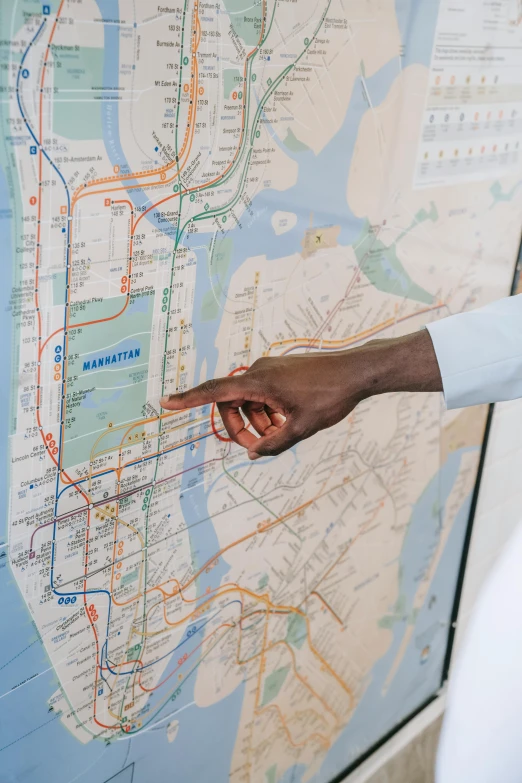 a man pointing at a map on a wall, by Jessie Algie, trending on unsplash, harlem, orange line, 🚿🗝📝