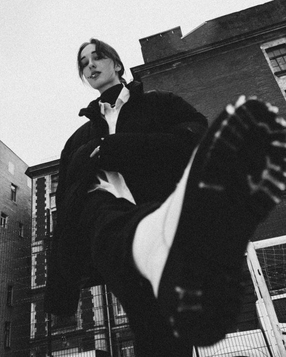 a black and white photo of a man on a skateboard, a black and white photo, by Emma Andijewska, unsplash, realism, billie eilish as a nun, massive boots, beautiful androgynous prince, in a rooftop