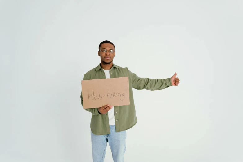 a man in a green shirt is holding a sign, by Niko Henrichon, trending on pexels, light-brown skin, background image, full body pose, guide