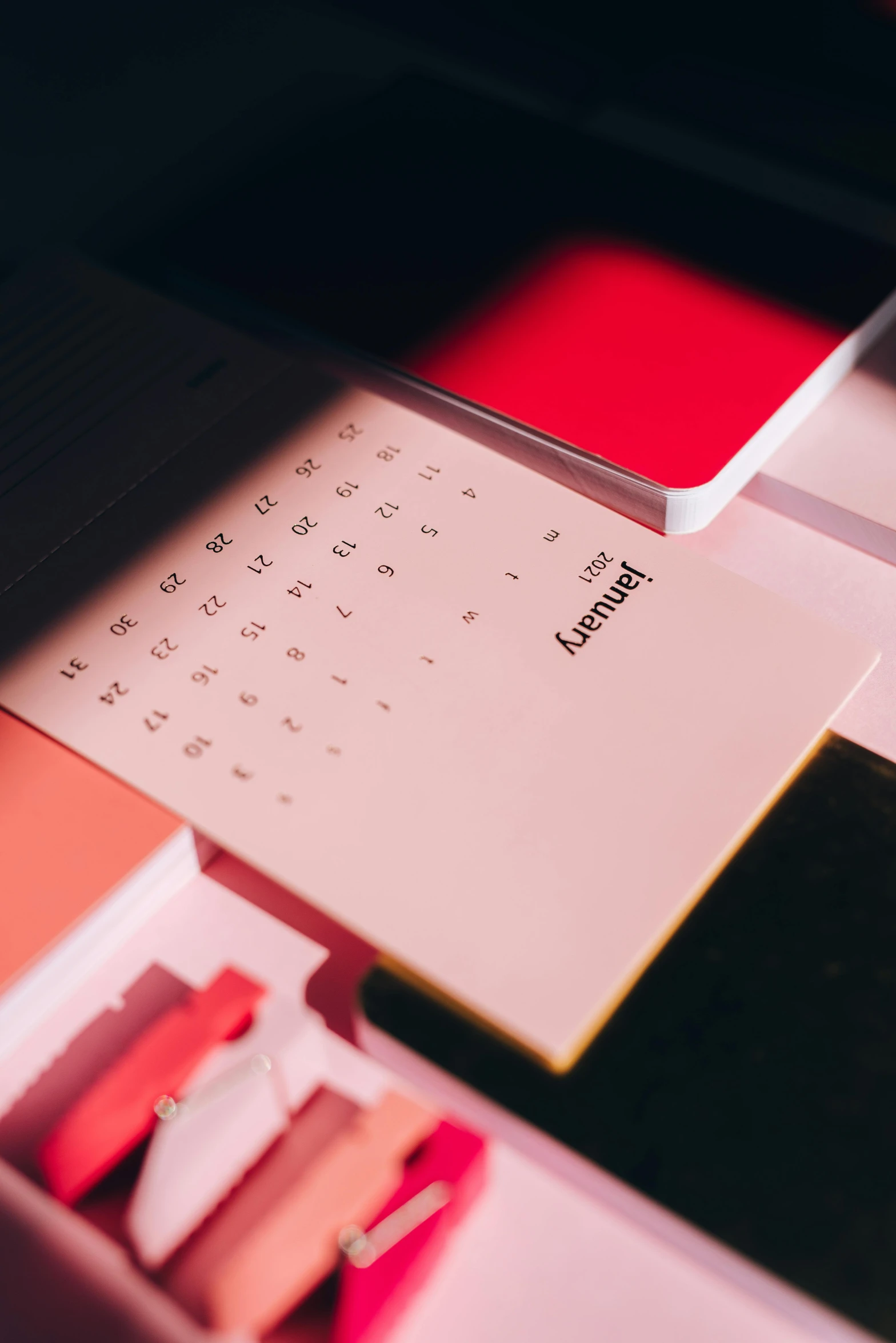 a calendar sitting on top of a desk next to a keyboard, by Carey Morris, trending on unsplash, pink and red color scheme, thumbnail, material design, luxury journal cover