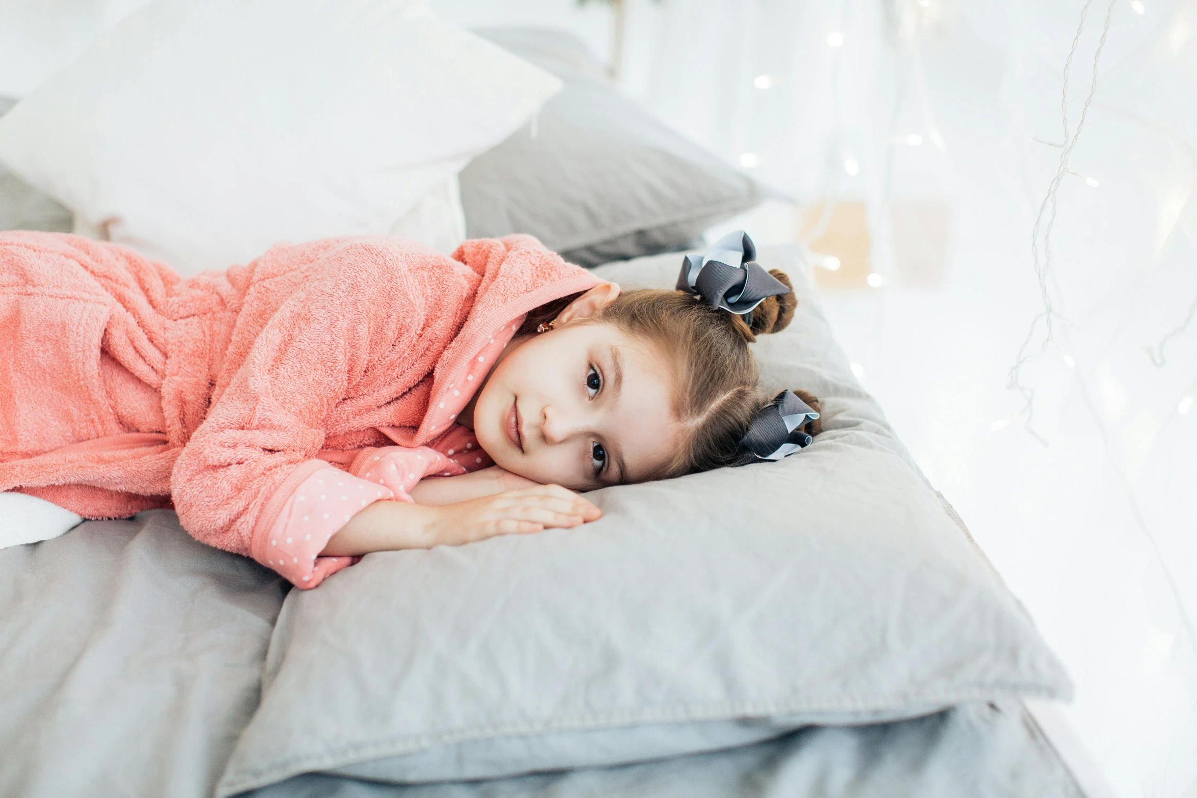 a little girl laying on top of a bed, by Emma Andijewska, pexels, wearing a grey robe, disappointed, covered in coral, teenage girl