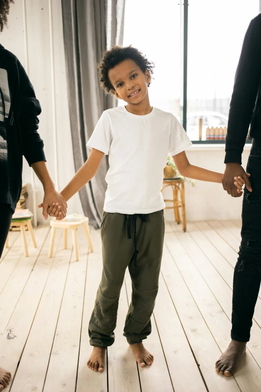 a group of people holding hands in a room, young boy, baggy pants, caring fatherly wide forehead, promo image