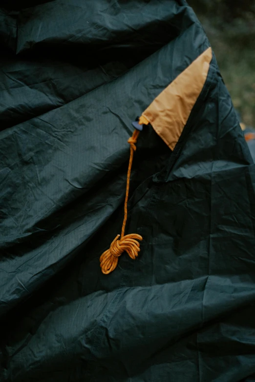 a blanket sitting on top of a wooden bench, by Jan Tengnagel, unsplash, process art, parachutes, black and orange coat, tent, high angle close up shot