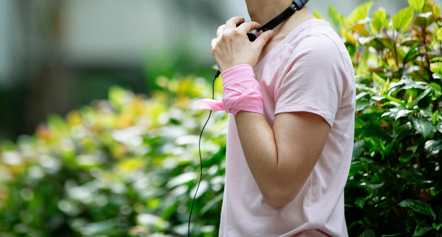 a man in a pink shirt is talking on a cell phone, an album cover, pexels, bandage on arms, hangzhou, nature outside, wearing fitness gear