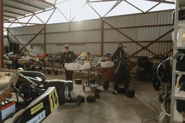 a group of men working on motorcycles in a garage, unsplash, process art, formula 1 garage, crates and parts on the ground, avatar image, lachlan bailey