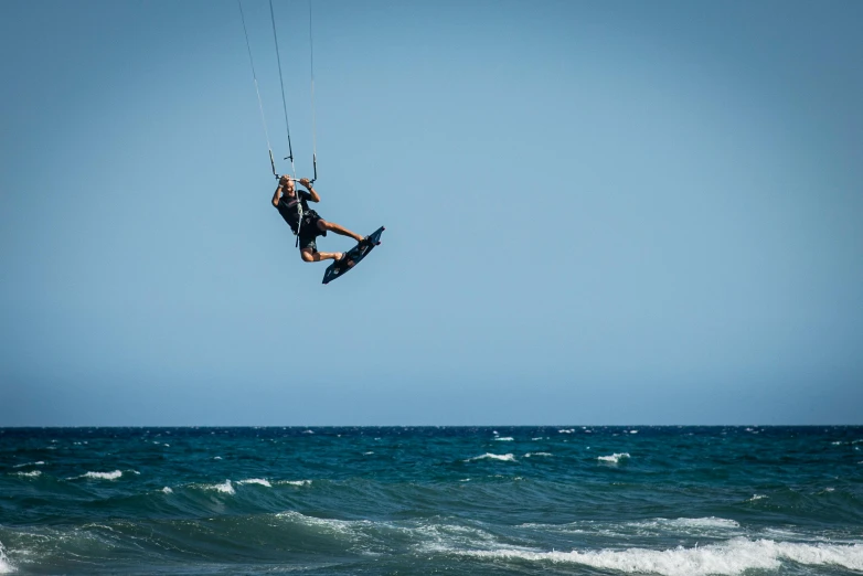 a man flying through the air while riding a kiteboard, by Niko Henrichon, pexels contest winner, arabesque, cyprus, blue sky, hanging rope, looking to the right