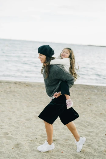 two girls playing with a frisbee on the beach, by Nina Hamnett, unsplash, minimalism, with black beanie on head, girl is running, motherly, with cape