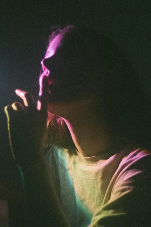 a woman holding a microphone in a dark room, a picture, inspired by Elsa Bleda, synchromism, praying with tobacco, glowing with colored light, young woman looking up, brightly colored