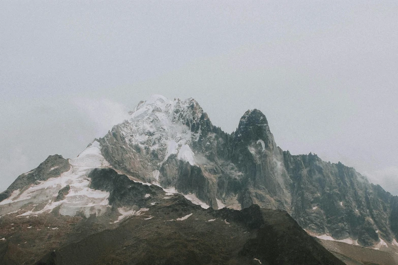 a large mountain covered in snow on a cloudy day, an album cover, unsplash contest winner, craggy, grey, larapi, 2000s photo