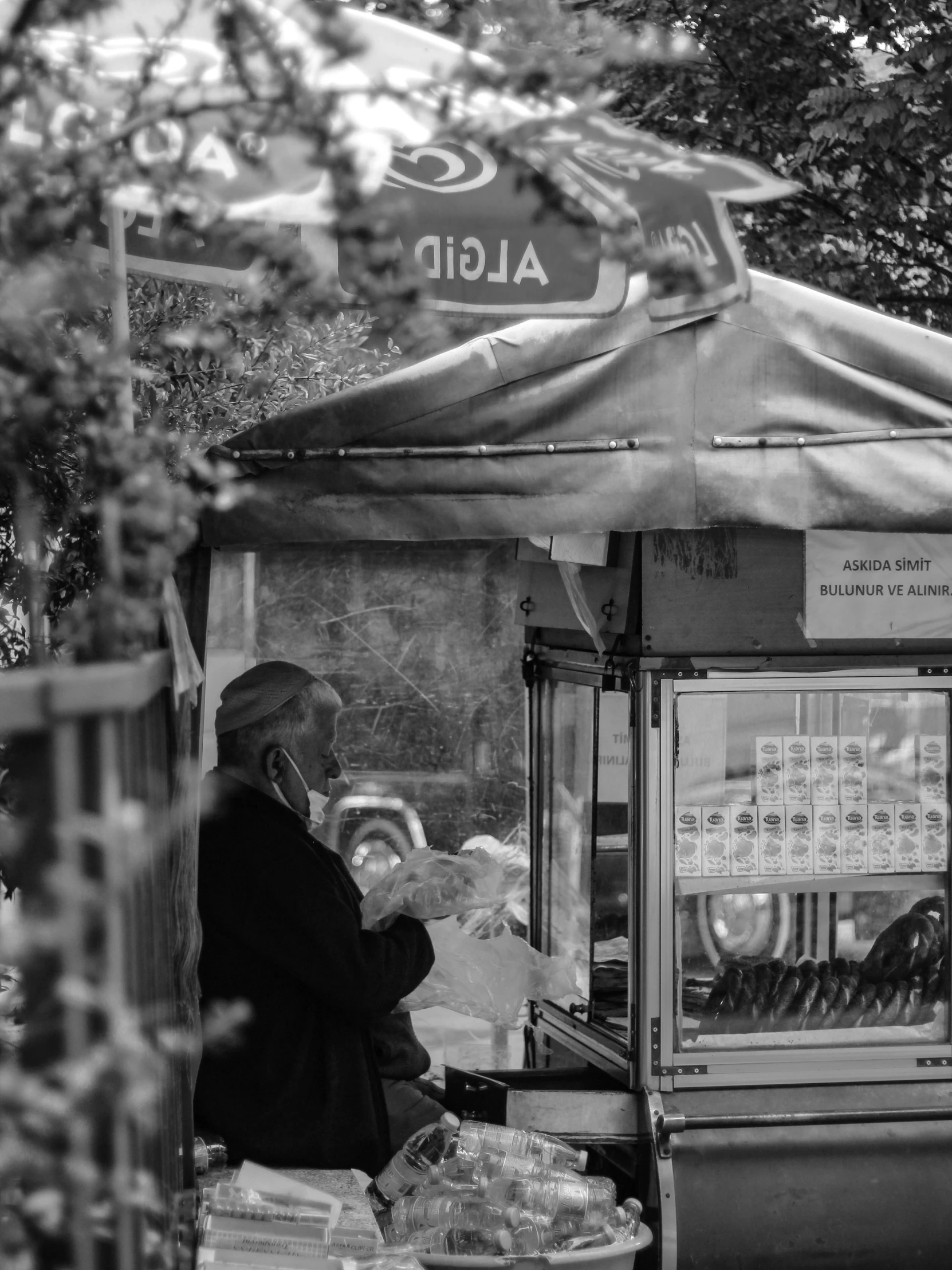 a man standing in front of a food stand, a black and white photo, by Kristian Kreković, fine art, old man doing with mask, real picture taken in zoo, 15081959 21121991 01012000 4k, vending machine