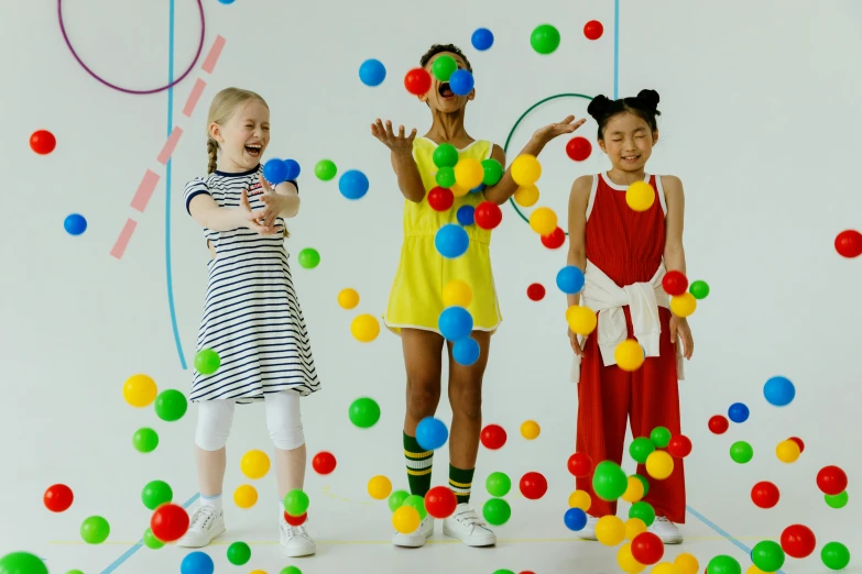 a group of young girls standing next to each other, inspired by Yayou Kusama, interactive art, in a ball pit, studio photoshoot, primary colours, ad image