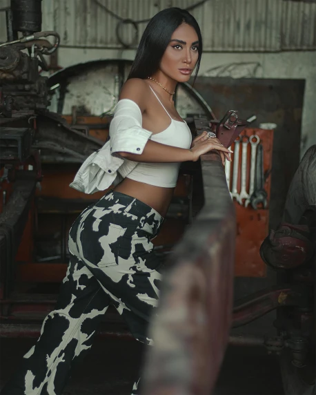 a woman in a white top and black and white pants, a colorized photo, trending on pexels, mechanic, indonesia, barn, fashion shoot 8k