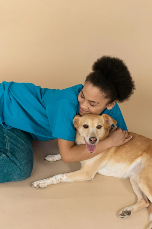 a woman laying on the floor with a dog, inspired by Elke Vogelsang, teal studio backdrop, hugging and cradling, surgery, caramel