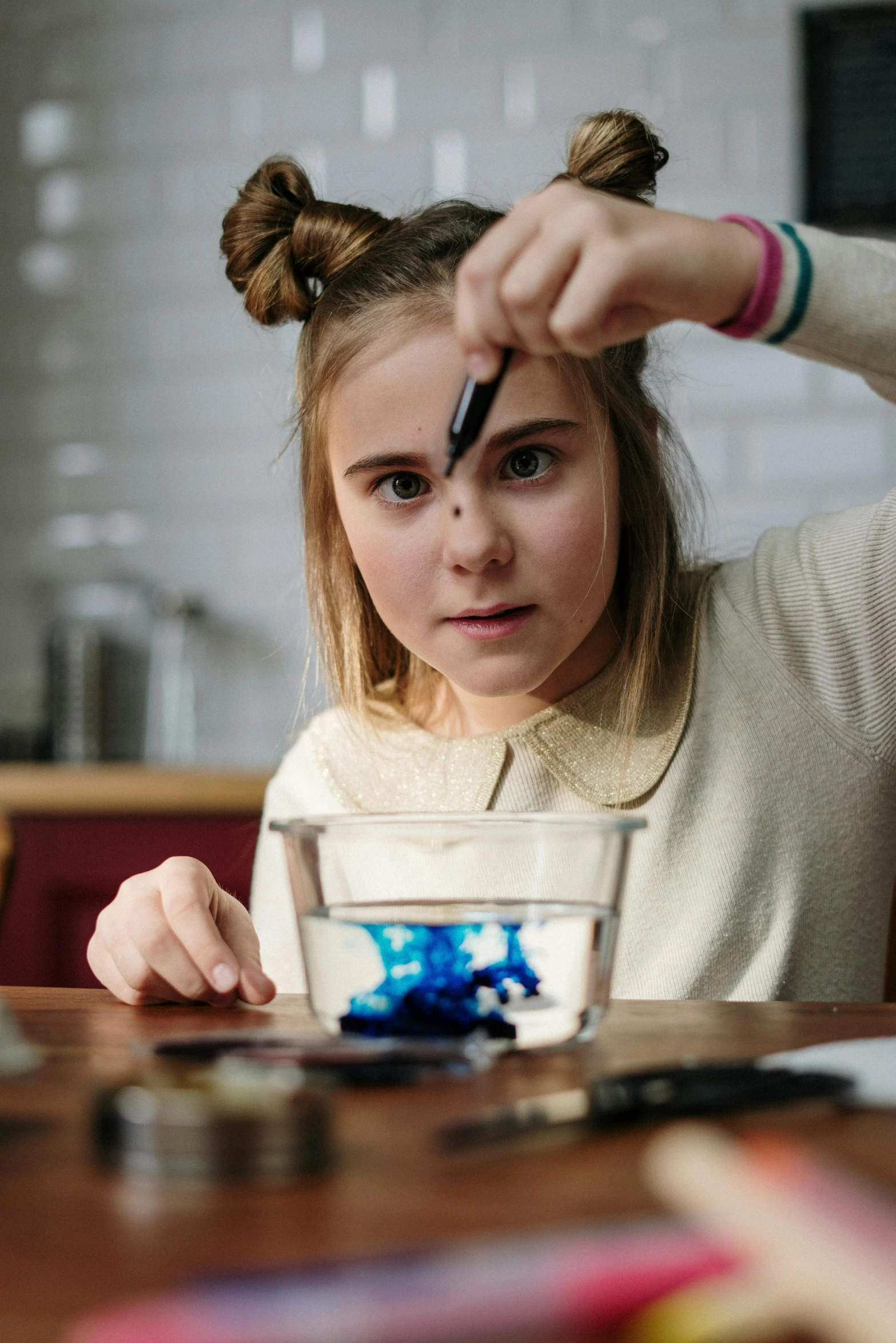 a little girl sitting at a table with a pen in her hand, pexels contest winner, process art, scientific glassware, teenage girl, oil slick in the water, concentrated look