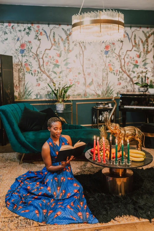 a woman sitting in a living room reading a book, maximalism, stunning african princess, lit candles, gold and teal color scheme, on the altar