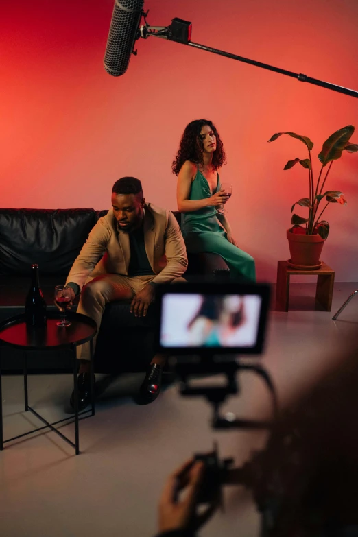 a woman sitting on top of a couch next to a man, trending on pexels, performing a music video, at a fashion shoot, full scene camera shot, promotional image