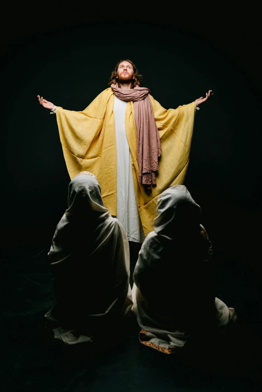 jesus standing in the dark with his arms wide open, by Everett Warner, pexels, the three fates, yellow robe, studio photo, ( ( theatrical ) )