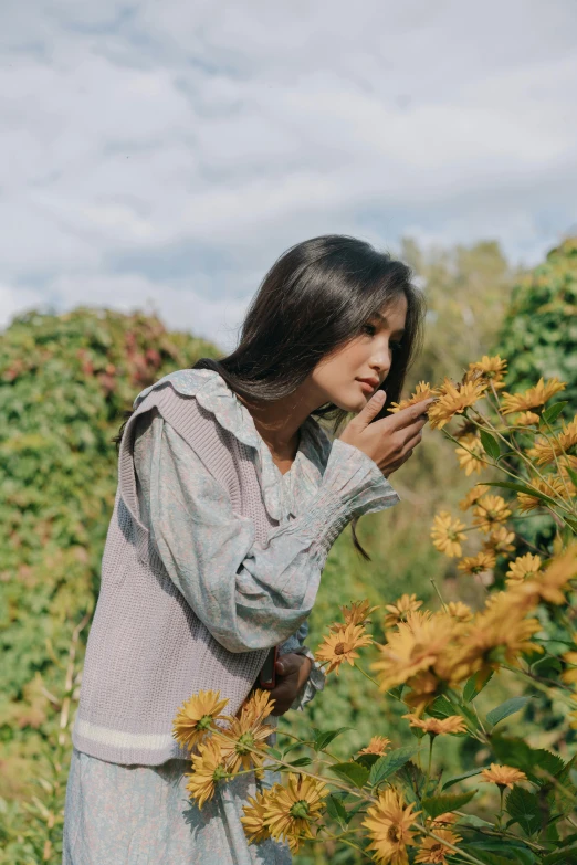 a woman standing in a field of yellow flowers, freida pinto, in a cottagecore flower garden, thoughtful pose, in fall