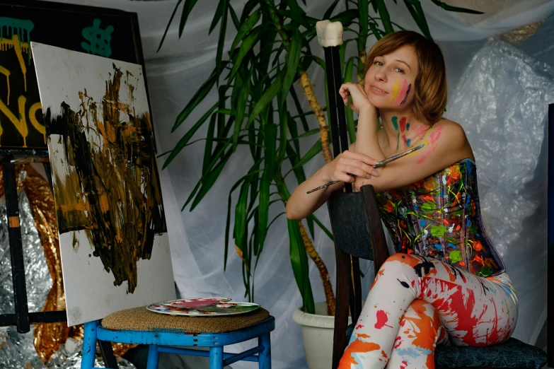 a woman sitting on a chair in front of a painting, inspired by Nadya Rusheva, inside a grand messy studio, promo photo, ((portrait)), colorful scene