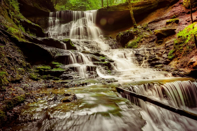 a waterfall flowing through a lush green forest, an album cover, pexels contest winner, yorkshire, thumbnail, brown, sandfalls