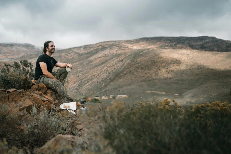 a man sitting on top of a rocky hill, a portrait, by Lee Loughridge, pexels contest winner, food. craft and adventure, sitting on a table, avatar image