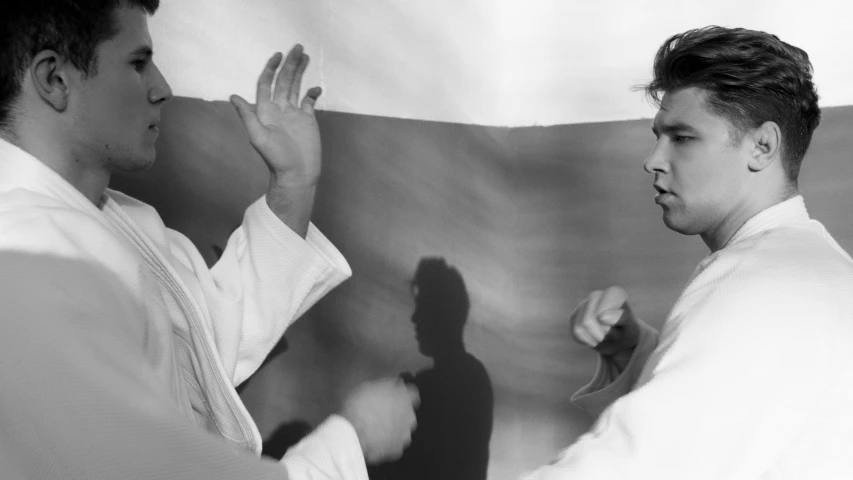 a couple of men standing next to each other, a black and white photo, unsplash, figuration libre, karate, helene frankenthaler, fighting with angles, wearing white robes