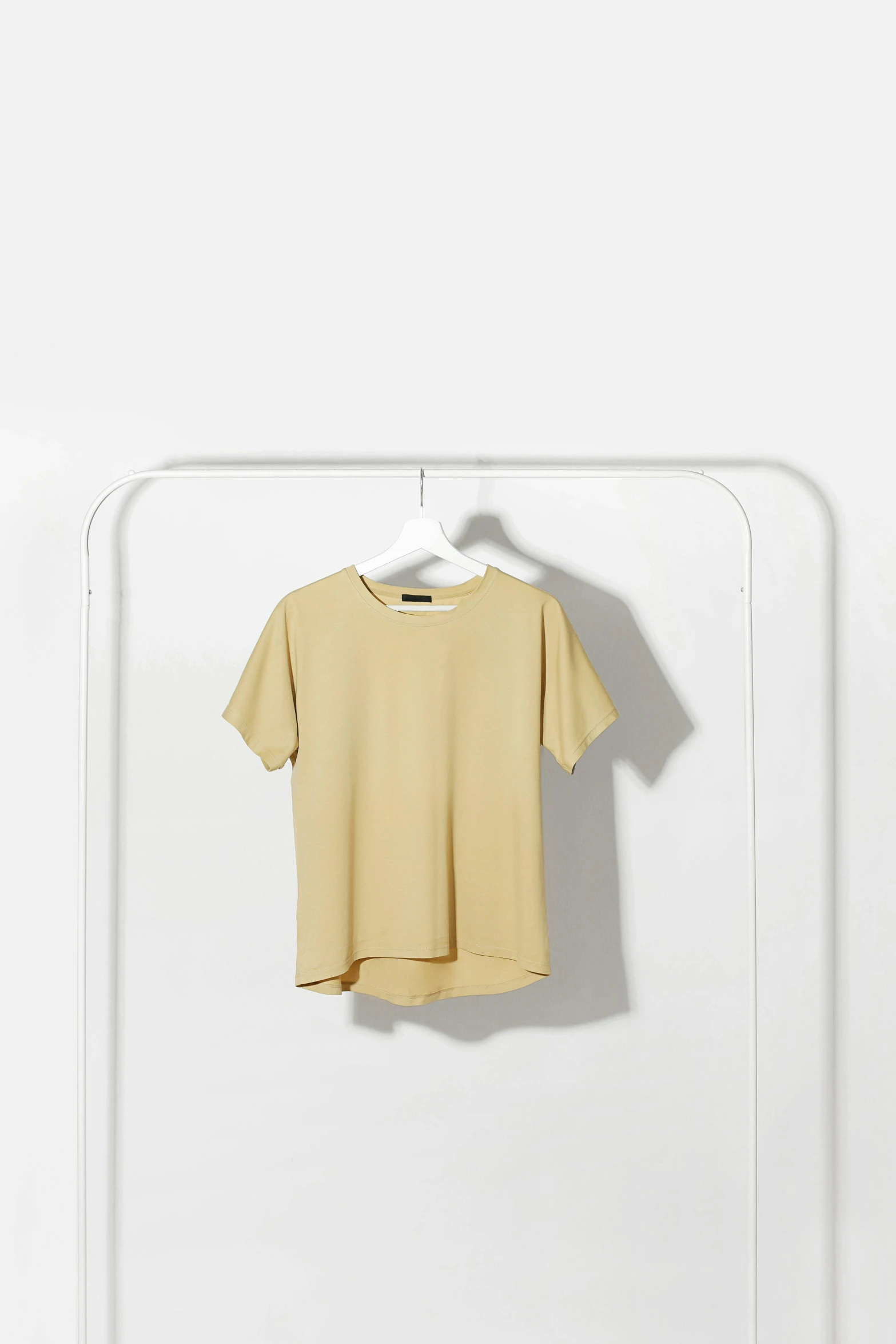 a t - shirt hanging on a clothes rack, by Mi Fu, minimalism, banana color, dolman, thumbnail, smooth in _ the background