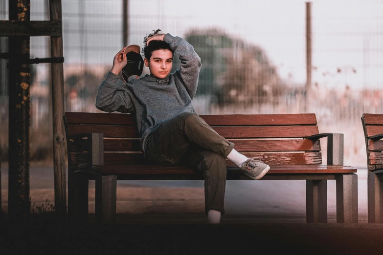 a man sitting on top of a wooden bench, by Niko Henrichon, pexels contest winner, realism, male teenager, ears, androgynous male, 1 6 years old