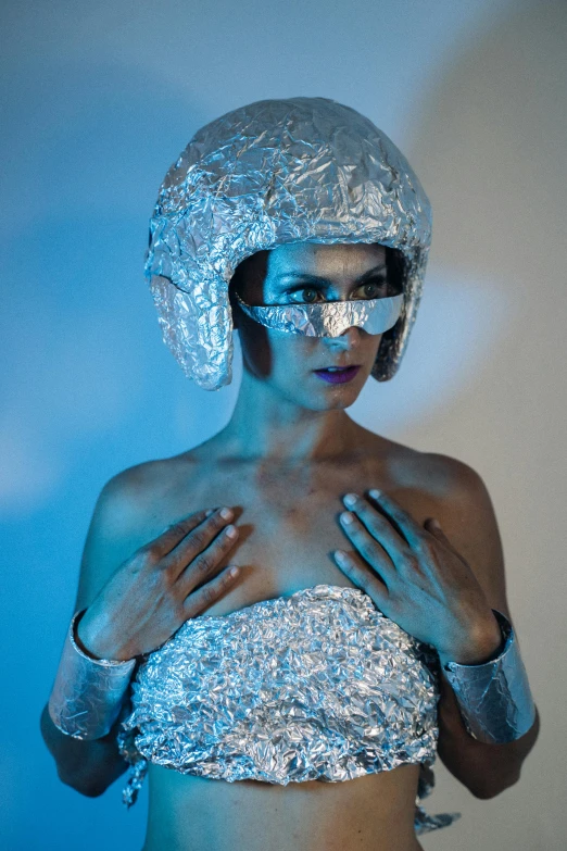 a woman in silver is posing for a picture, inspired by hajime sorayama, unsplash, wearing an astronaut helmet, covered in bandages, studio photo, blue and silver