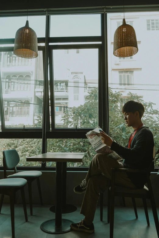 a man sitting in a chair reading a newspaper, by Sebastian Vrancx, pexels contest winner, hoang long ly, cafe interior, teenage boy, gif