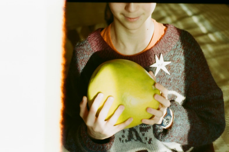 a woman holding a green apple in her hands, a polaroid photo, by Nathalie Rattner, starry, wearing a melon, coconuts, wearing a green sweater