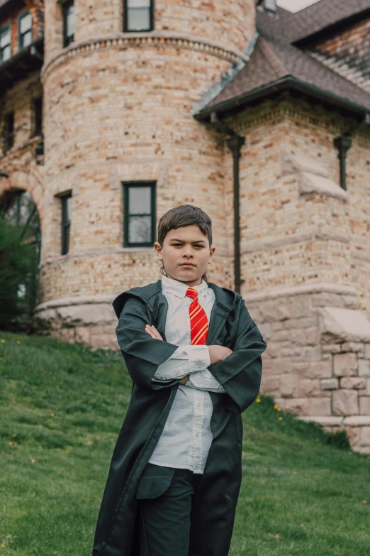 a young man standing in front of a castle, by Fuller Potter, unsplash, dressed as a wizard, barron trump, professional cosplay, arms folded