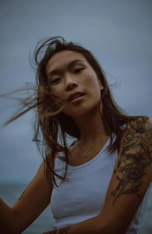 a woman with her hair blowing in the wind, a tattoo, trending on pexels, young cute wan asian face, ( ( ( kauai ) ) ), editorial model, looking menacing