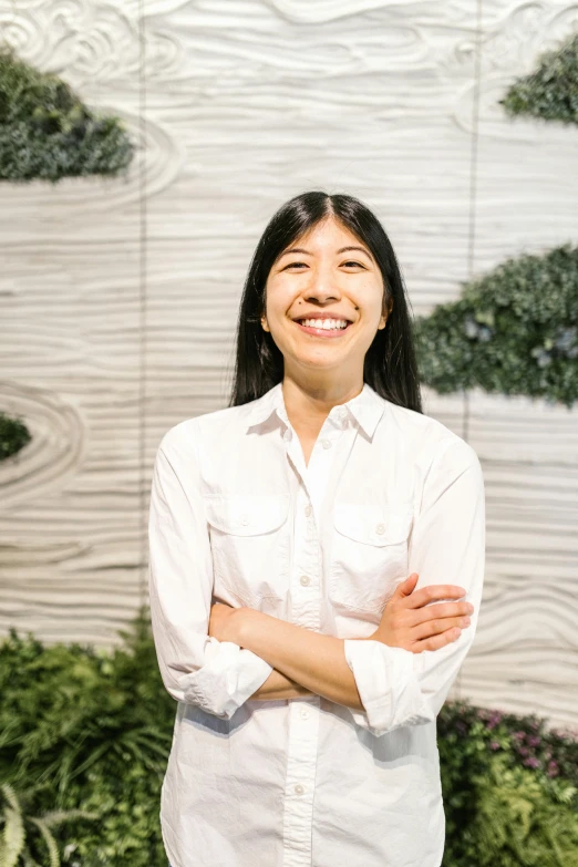 a woman standing in front of a wall of plants, trending on unsplash, shin hanga, smiling slightly, engineer, profile image, robert kondo