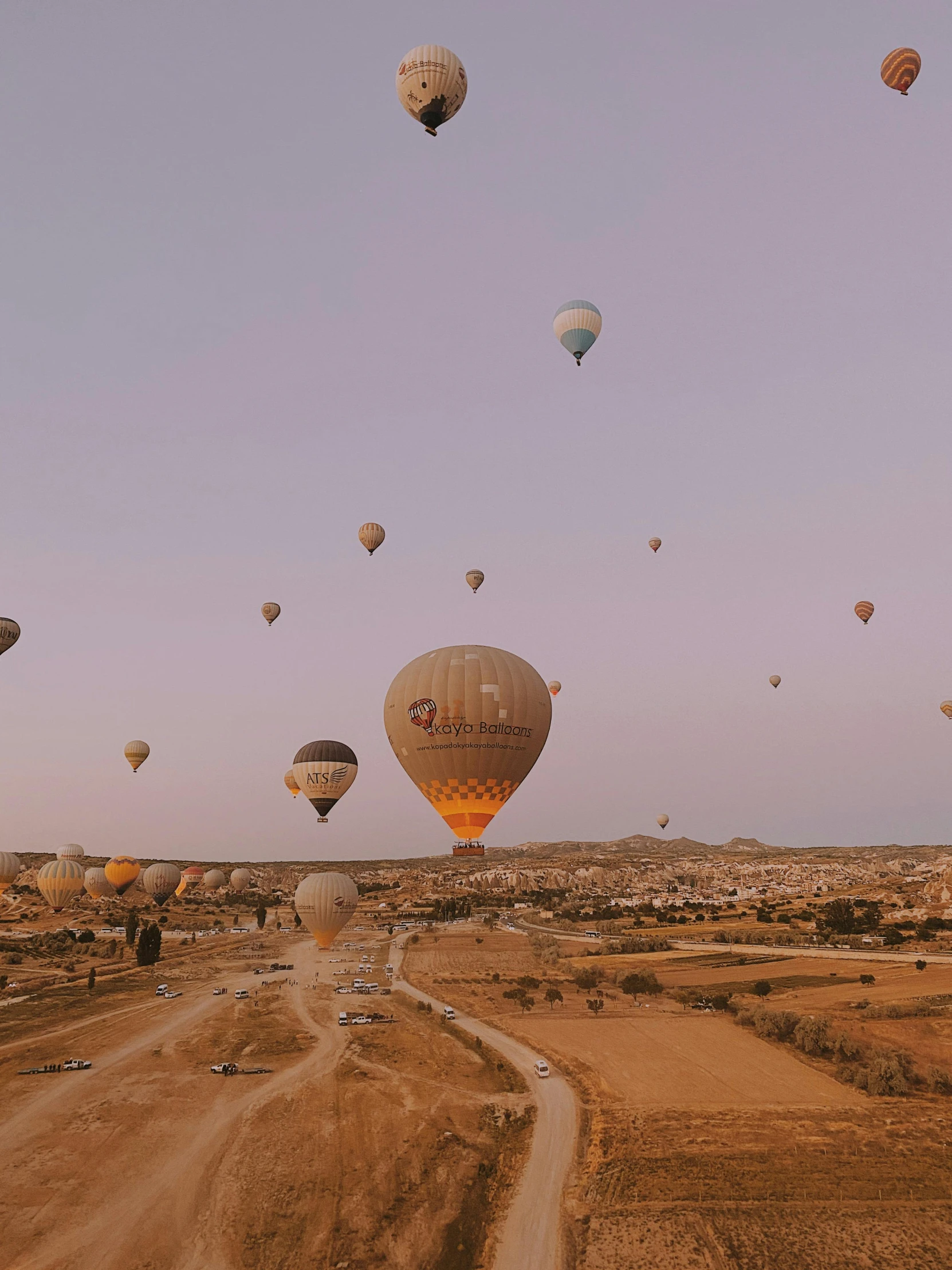 many hot air balloons flying over a dirt road, pexels contest winner, cinematic blue and gold, old town mardin, golden hour 8 k, helicopter view