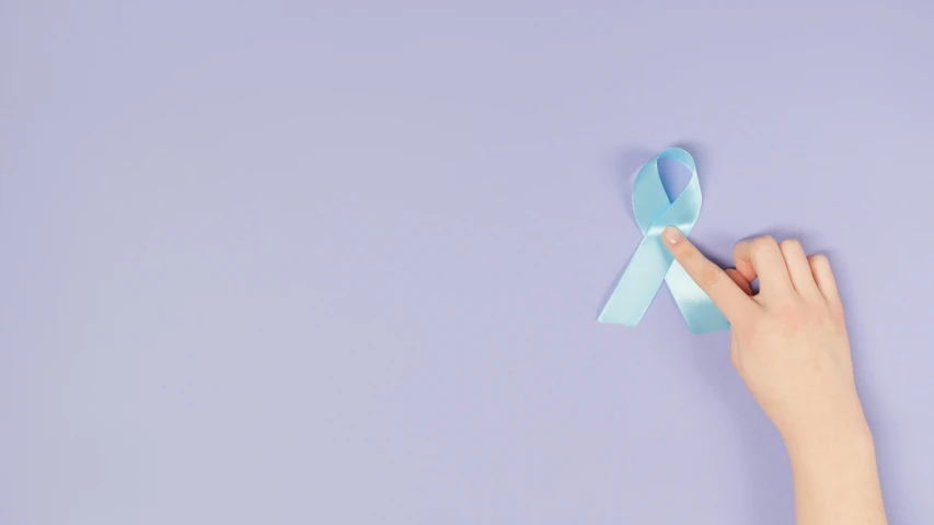 a woman's hand holding a blue ribbon on a purple background, by Sebastian Vrancx, pexels contest winner, wearing a light blue shirt, nursing, full body image, tumours