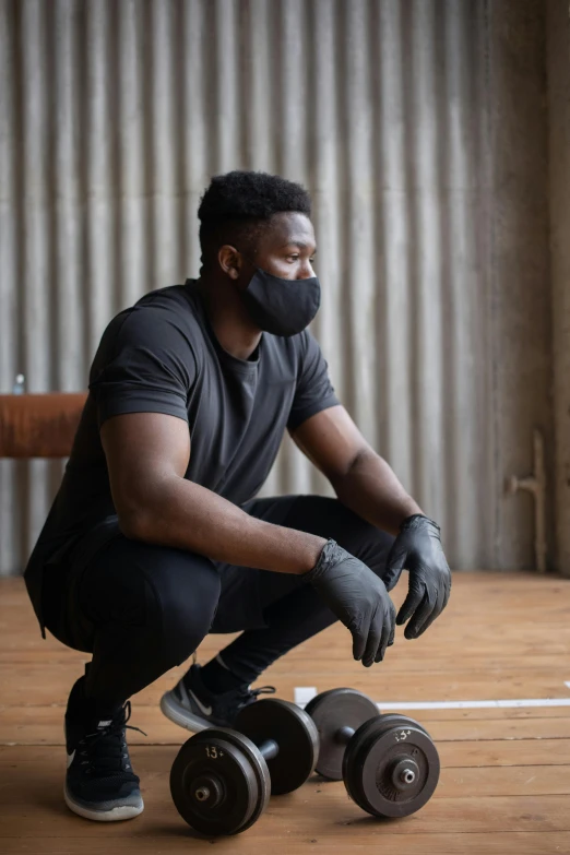 a man sitting on top of a skateboard on a wooden floor, black facemask, lifting weights, jaylen brown, contemplative