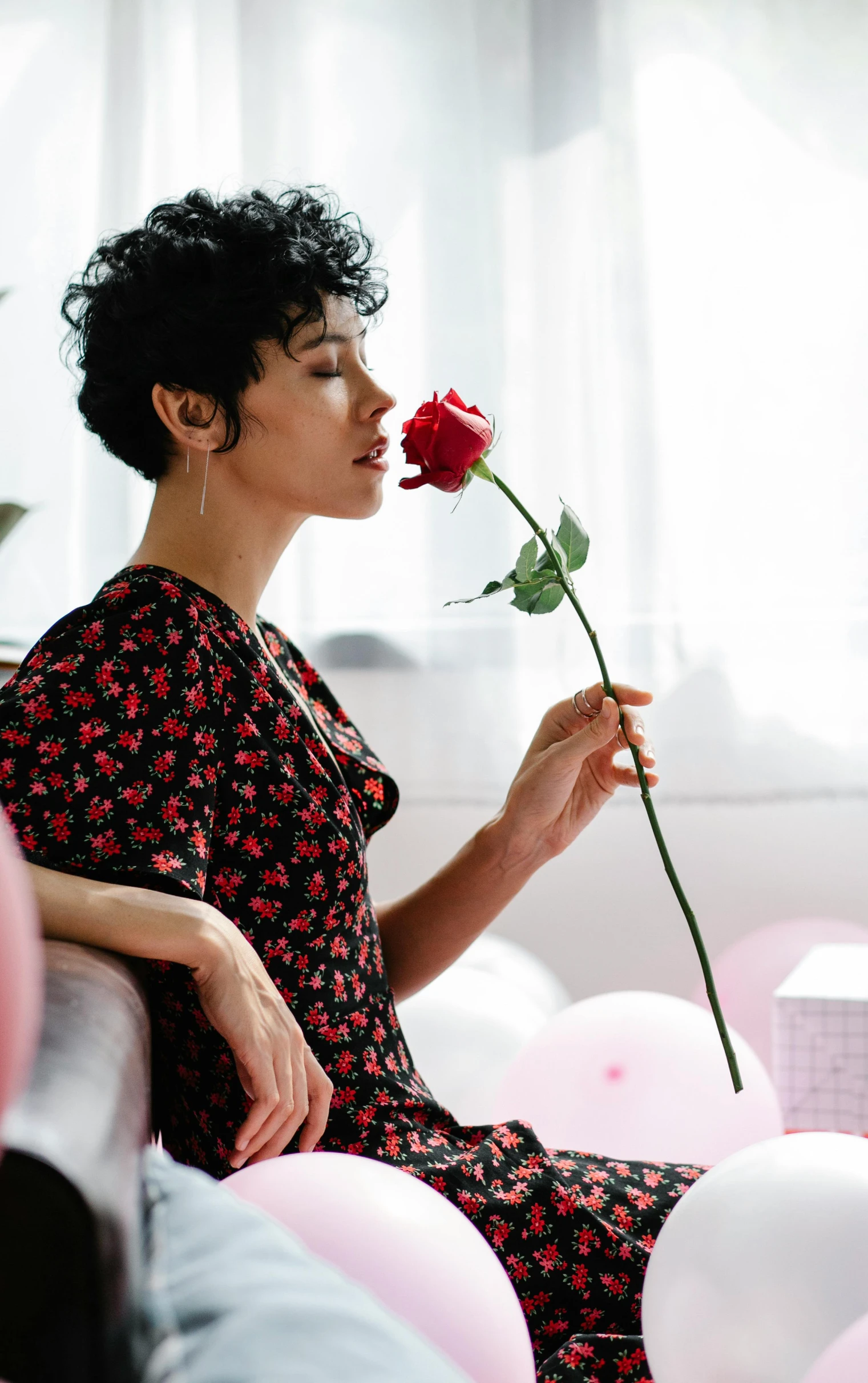 a woman sitting on a couch holding a rose, pexels, dreaming of kissing a girl, kiko mizuhara, - 9, flowers grow from the body