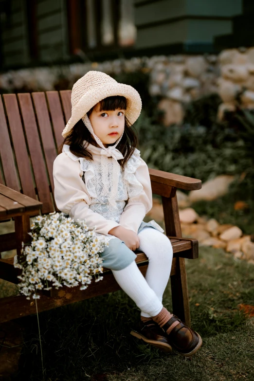 a little girl sitting on top of a wooden bench, inspired by Kate Greenaway, pexels, in style of lam manh, dressed with fluent clothes, in a comfortable chair, ulzzang