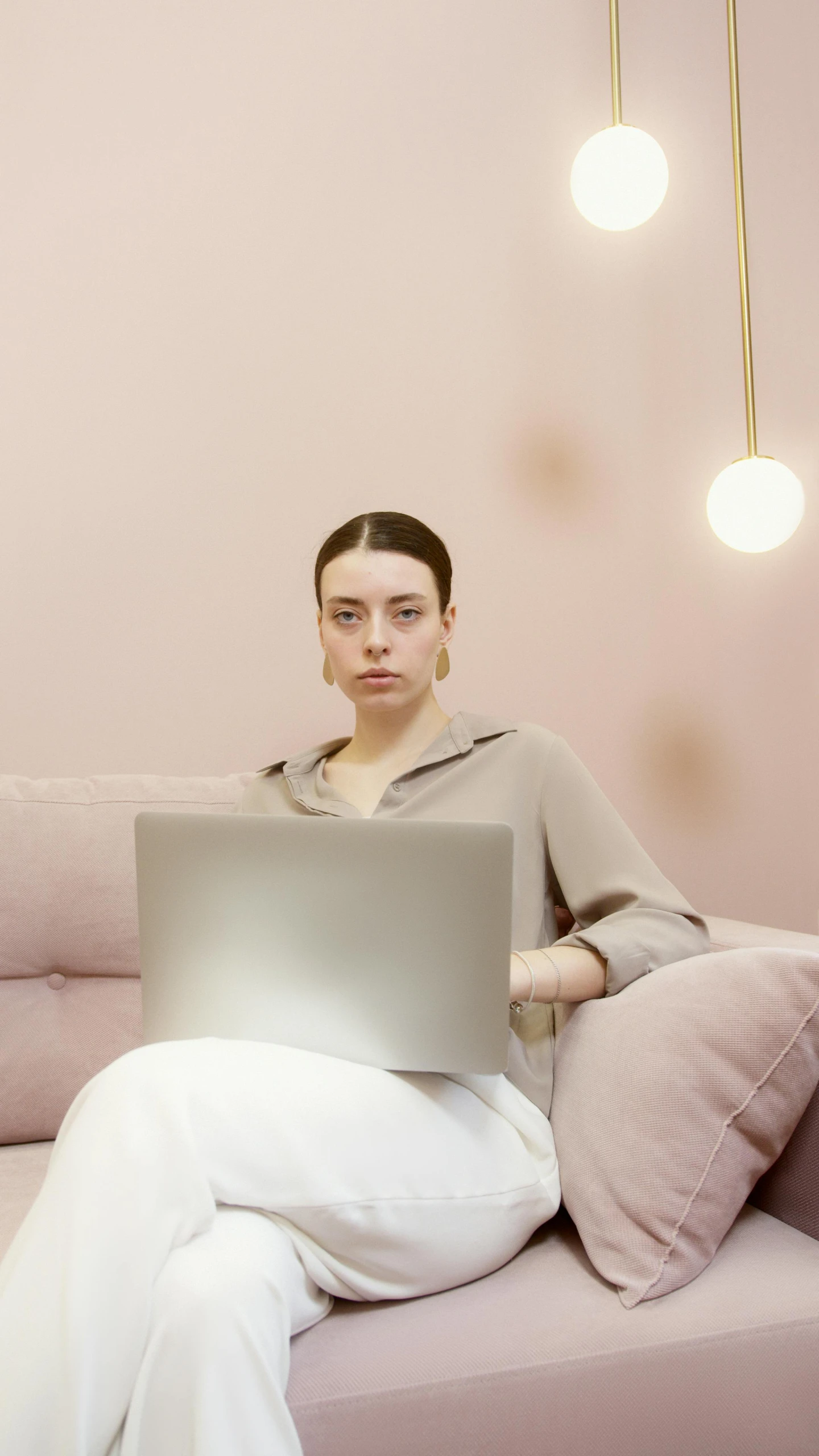 a woman sitting on a couch with a laptop, a colorized photo, trending on pexels, minimalism, pink skin, serious face, in office, low quality photo