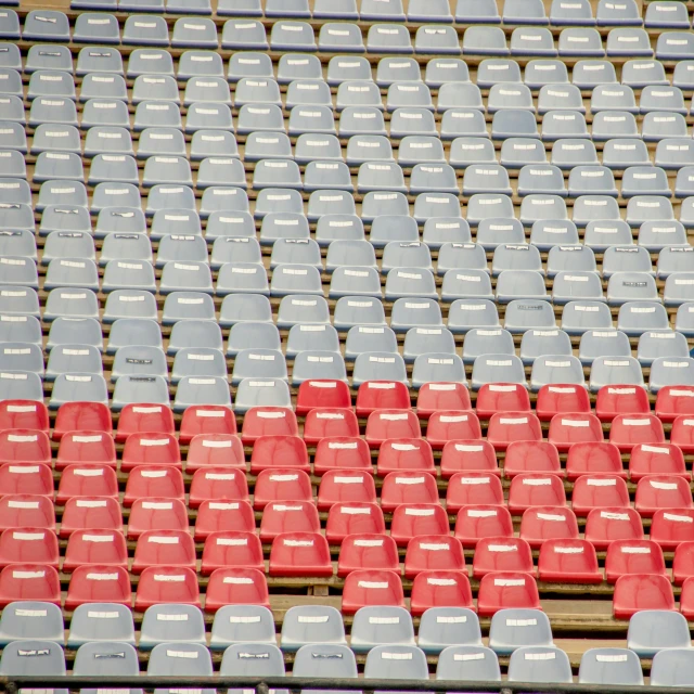 a man standing on top of a tennis court holding a racquet, inspired by Andreas Gursky, flickr, color field, hundreds of chairs and tables, red and grey only, standing in a stadium, sitting in a plastic throne