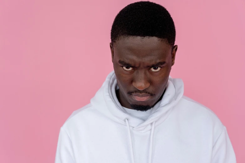 a man in a white hoodie on a pink background, by Barthélemy Menn, trending on pexels, les nabis, looking threatening, ( ( dark skin ) ), incompetent, complaints