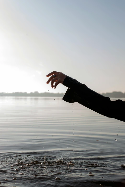 a person reaching out of the water to catch a frisbee, inspired by Jan Rustem, the thames is dry, floating crystals, wet climate, looking partly to the left