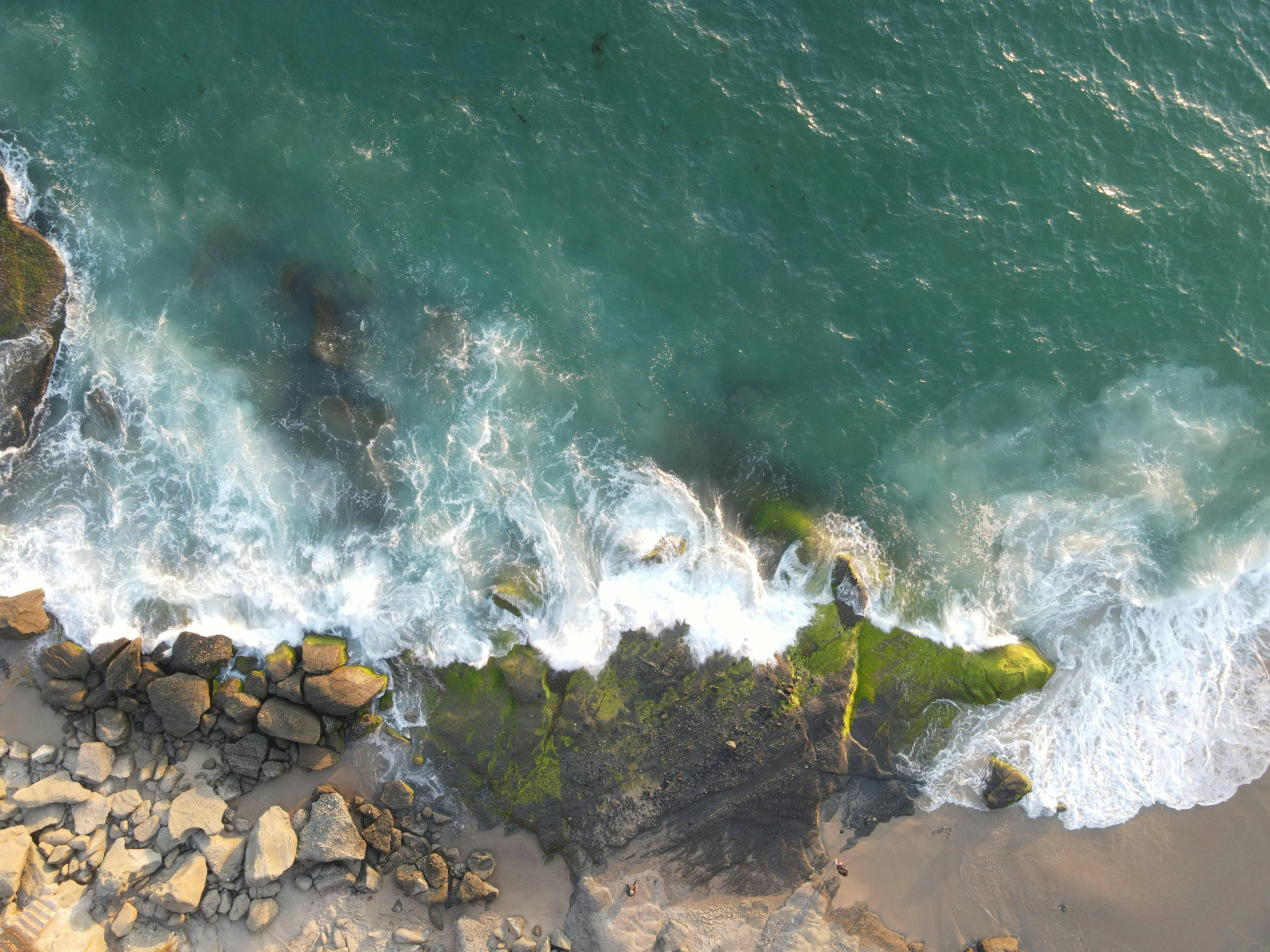 a large body of water next to a rocky shore, pexels contest winner, happening, birdseye view, oceanside, video still, a green