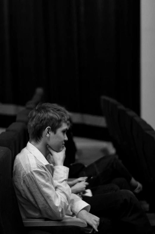 a black and white photo of a man sitting in a chair, flickr, happening, vitalik buterin, sitting in a movie theater, sideview, musician